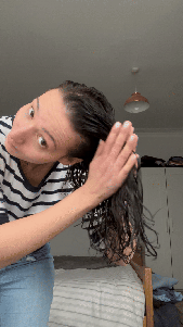 Natalie uses a praying hands motion to smooth a curl gel through her hair, then she scrunches her hair all over.