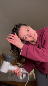Natalie uses a hairdryer with a diffuser to dry her curls by cupping them in the diffuser attachment.