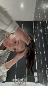 Natalie scrubs her scalp with the pads of her fingers to work in her shampoo.